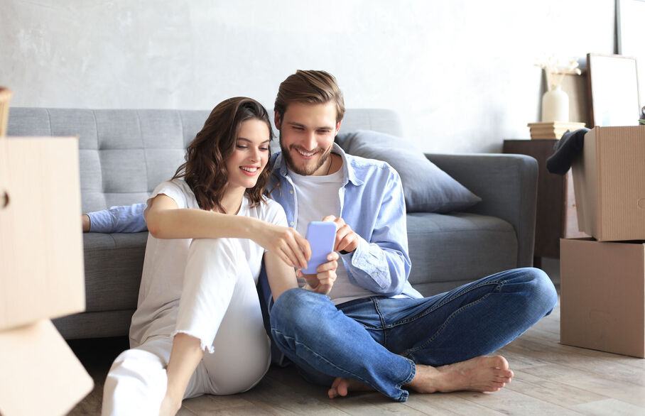 Two people sitting on the floor looking at a phone