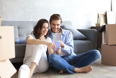 Two people sitting on the floor looking at a phone