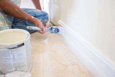 Close up of someone painting skirting 