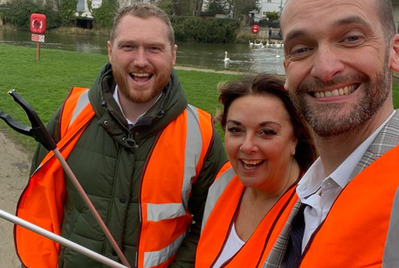 Three people posing in hi-vis jackets with a litter picker