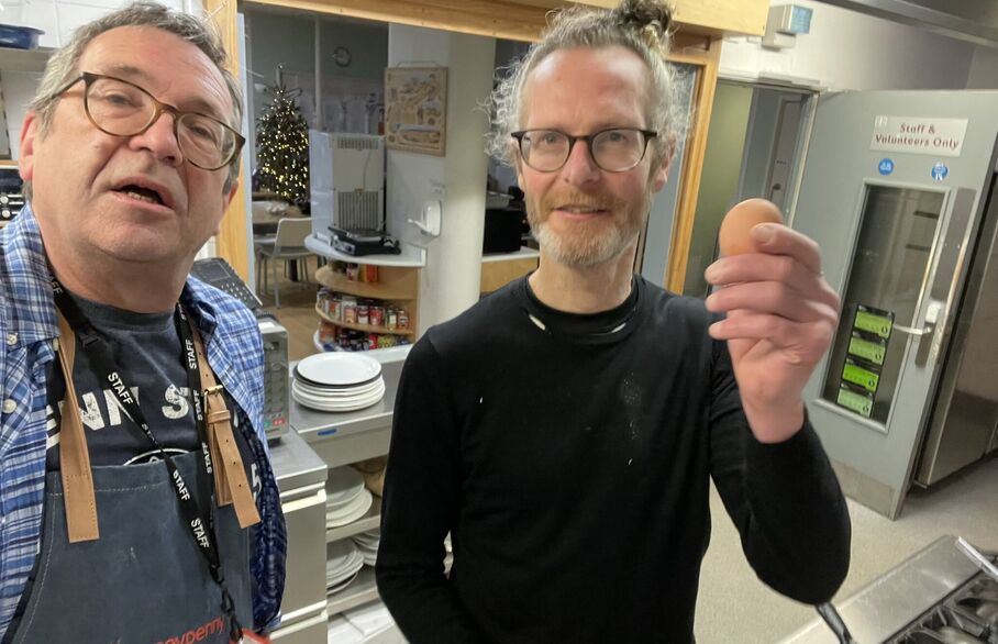 Two people standing in a kitchen, one holding an egg