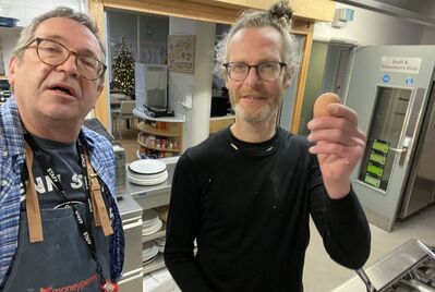 Two people standing in a kitchen, one holding an egg