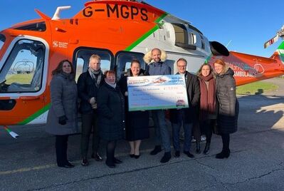 A group of people standing in front of a helicopter