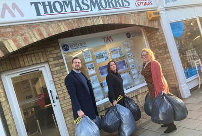 A group of people holding bin bags in front of the Thomas Morris building