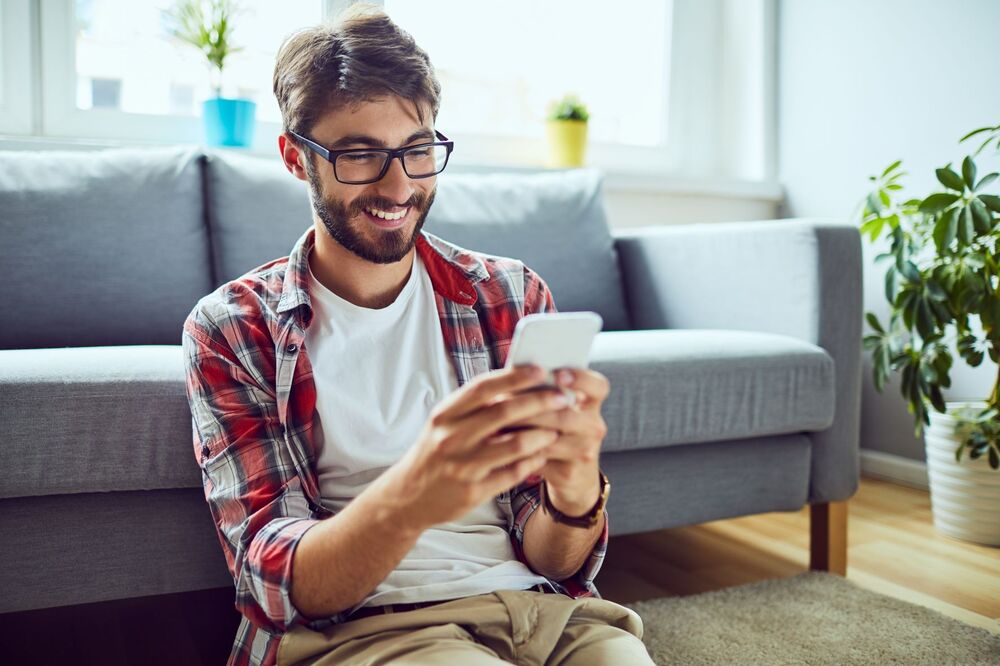 young man sitting on floor checking conveyancing progress