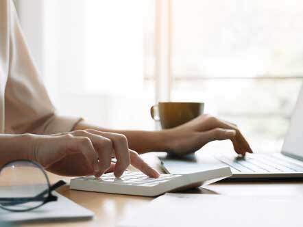 Close up hand of woman using computer calculating household finances