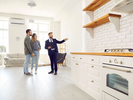 An estate agent showing a couple around a kitchen
