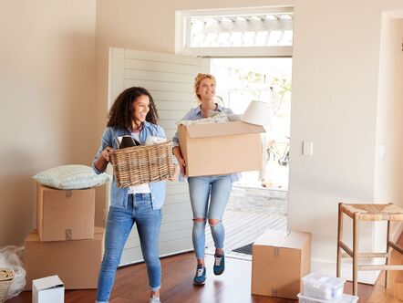 A couple moving boxes inside a house