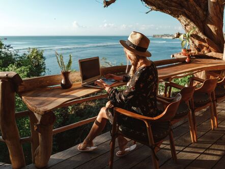 Someone typing on a laptop on a sea-front balcony